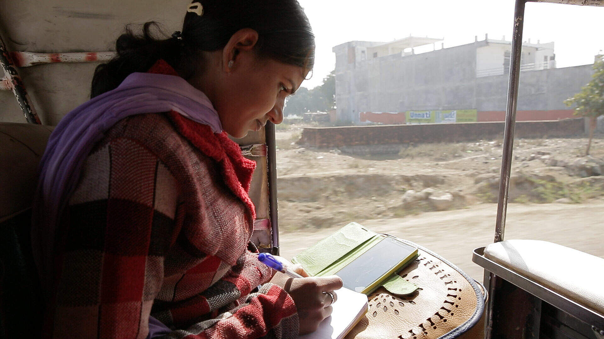 A young female journalist reads her phone.