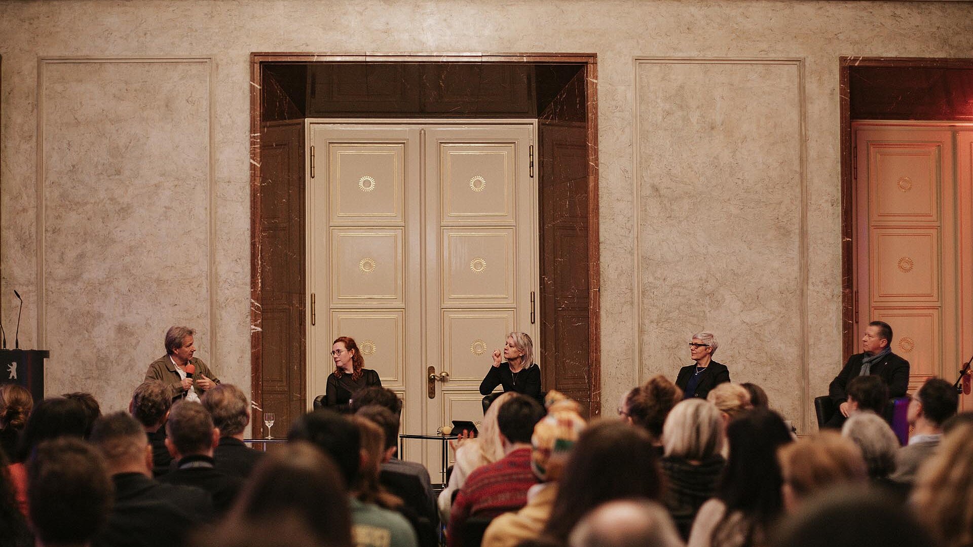 Panel Discussion at Rotes Rathaus - Five people sitting on a stage you can see them speaking. 